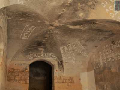 Sui muri notiamo scritte in stampatello che contrastano con il vecchio tufo divorato dal tempo